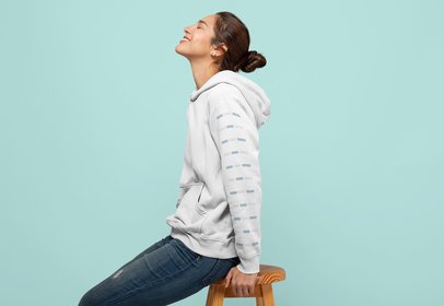 Mockup of a Woman Wearing a Pullover Hoodie Sitting on a Stool