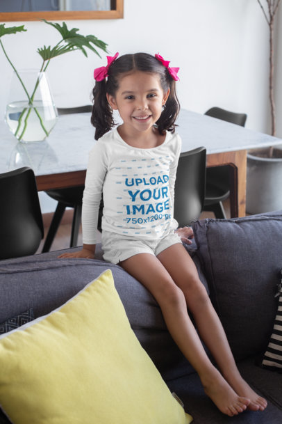 Long Sleeve T-Shirt Mockup of a Little Girl with Bows Sitting on a Couch 