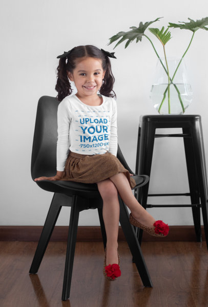 Long Sleeve Tee Mockup Featuring a Girl Sitting on a Chair Next to a Plant