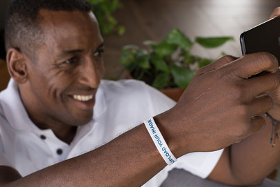 Silicone Wristband Mockup of a Man Holding his Phone 