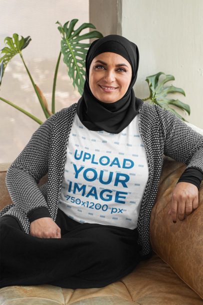 T-Shirt Mockup of a Woman Wearing a Hijab Sitting on a Couch
