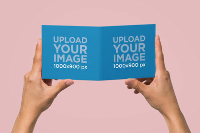 Mockup Featuring Two Hands Holding a Digipak at a Studio