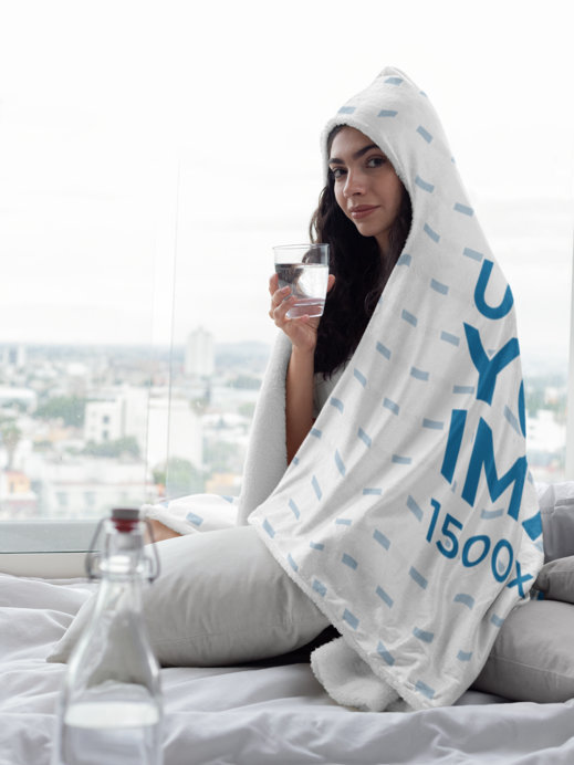 Hooded Fleece Blanket Mockup Featuring a Woman Holding a Glass of Water