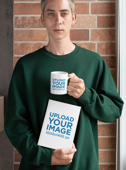 Mockup of a Young Man Posing with a Coffee Mug and a Book 
