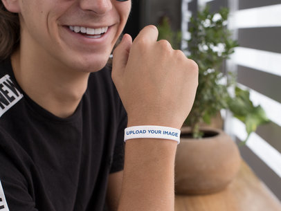 Silicone Wristband Mockup Featuring a Smiling Guy by a Plant Pot
