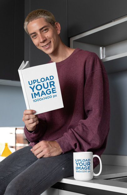 Mockup of a Young Man Holding a Book and Sitting Next to a 15 oz Coffee Mug 