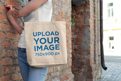 Tote Bag Mockup Featuring a Woman Standing by a Brick Wall 