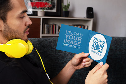 Mockup of a Man with Headphones Looking at a Digipak with a CD