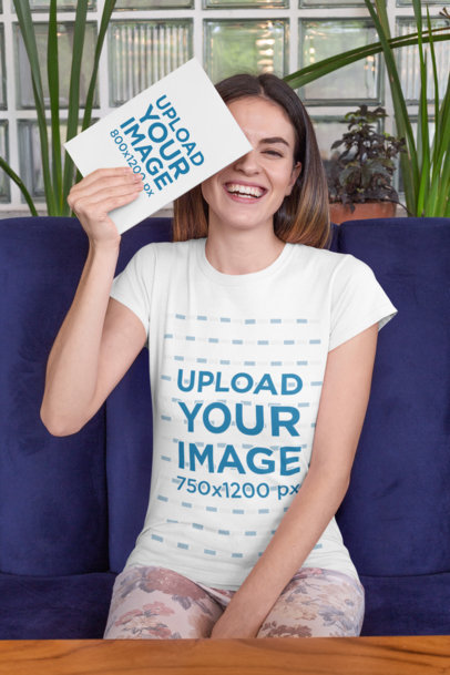 Mockup of a Joyful Woman Wearing a T-Shirt and Holding a Book in Front of Her Face 