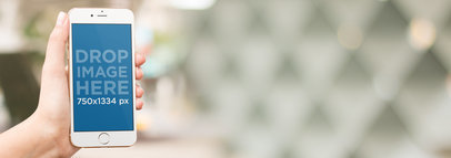 Mockup of a Woman Holding an iPhone Over a Blurred Background