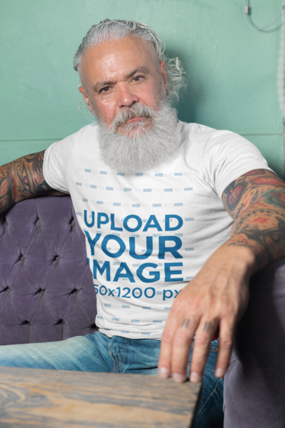 T-Shirt Mockup Featuring a Man Sitting on a Purple Sofa 28417