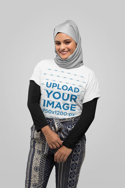 T-Shirt Mockup of a Young Woman Wearing a Hijab Against a Solid Color Backdrop 