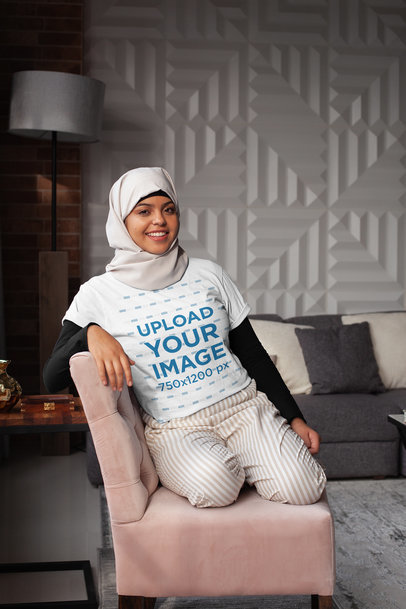 T-Shirt Mockup of a Woman Wearing a Hijab Casually Sitting on a Couch