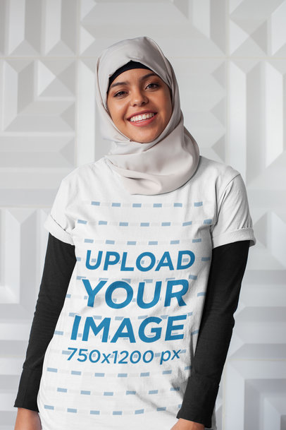 T-Shirt Mockup of a Woman with a Hijab Against a White Textured Wall