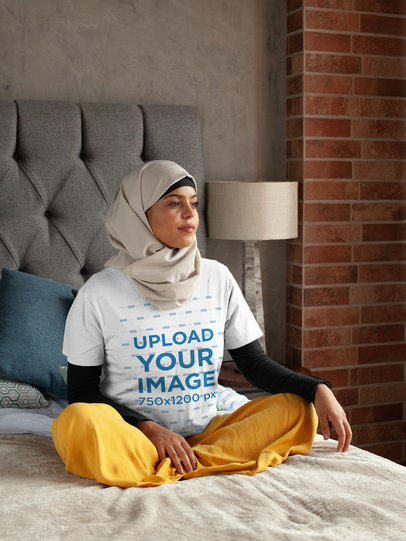 T-Shirt Mockup of a Woman in a Hijab Sitting Thoughtful on Her Bed