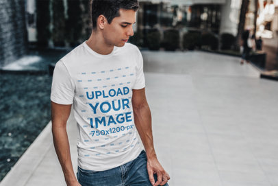 T-Shirt Mockup Featuring a Man Standing by a Modern Fountain 