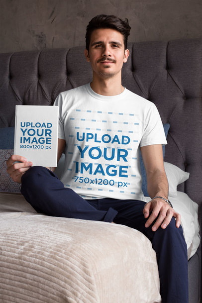 Mockup of a Man Wearing a T-Shirt and Holding a Book in His Bed
