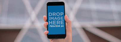 iPhone Mockup Being Used Outside a Modern Building