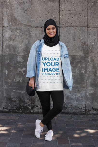 T-Shirt Mockup Featuring a Woman with a Hijab Against a Dark Stone Wall 