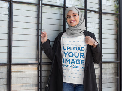 T-Shirt Mockup of a Woman Wearing a Hijab and Standing Next to a Large Window 28385