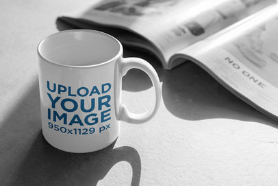 11 oz Coffee Mug Mockup Beside a Newspaper 404-el