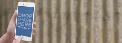 Mockup Template of a Person Holding an iPhone in Front of a Concrete Wall