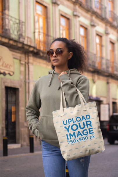 Tote Bag Mockup Featuring a Trendy Woman Walking by an Old Building