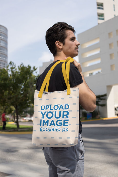Mockup of a Man Holding a Tote Bag with a Customizable Strap over His Shoulder