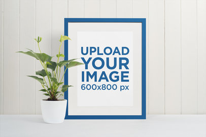 Picture Frame Mockup Featuring a White Wooden Wall and a Plant Pot 
