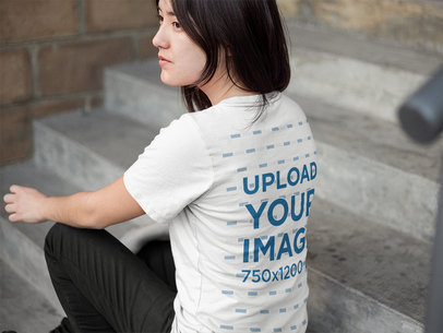 Back of an Asian Woman Wearing a Round Neck T-Shirt Mockup Sitting on a Stairway