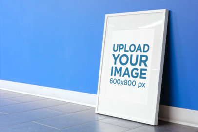 Poster Frame Mockup Leaning Against a Blue Wall