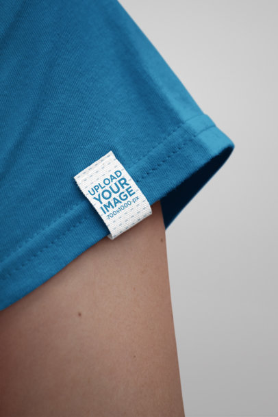 Mockup of a Woman Wearing a Shirt With a Clothing Label Attached to its Sleeve