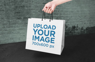 Mockup of a Hand-Held Paper Shopping Bag in a Cool Setting