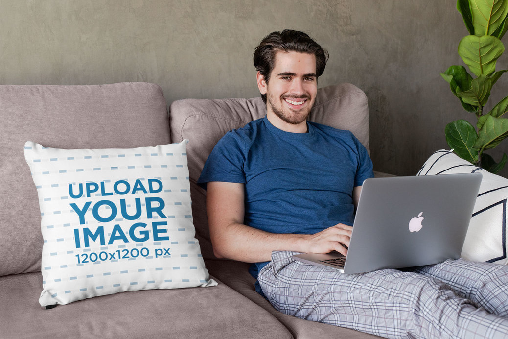 Square Pillow Mockup Featuring a Joyful Young Man Sitting on a Couch 