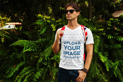 V-Neck T-Shirt Mockup Featuring a Young Man Standing in Front of Some Fern Bushes 
