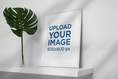Poster Frame Mockup Placed by a Palm Leaf in a Minimalistic Scenario