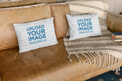 Mockup of Two Pillows on a Leather Sofa with Books on the Side
