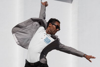 Embroidered Polo Shirt Mockup of a Man in a Blazer Jumping and Stretching His Arms