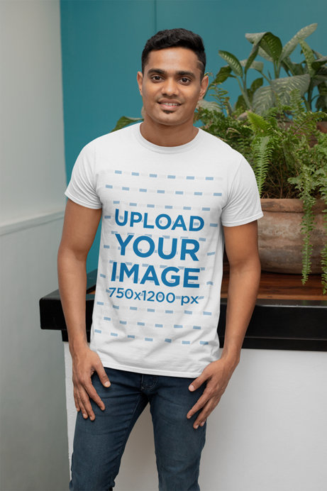 Mockup of a Man with a T-Shirt Posing Next to a Plant 