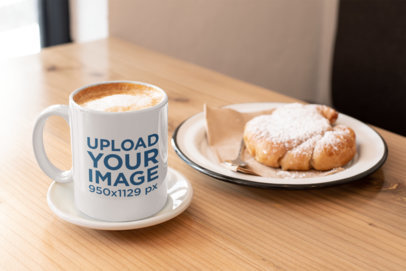 Mockup of an 11 oz Coffee Mug by a Croissant over a Wooden Table