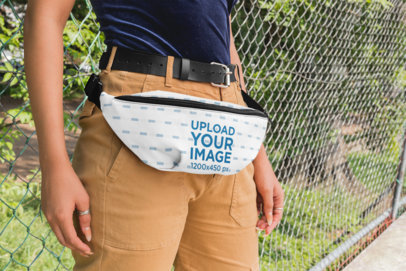 Mockup of a Woman With a Fanny Pack Leaning Against a Chain-link Fence 29141