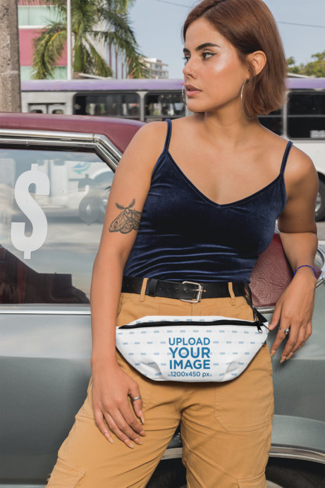 Mockup of a Woman with a Fanny Pack Leaning on an Old Car 