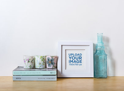 Photo Frame Mockup Standing on a Wooden Table Next to a Glass Bottle 