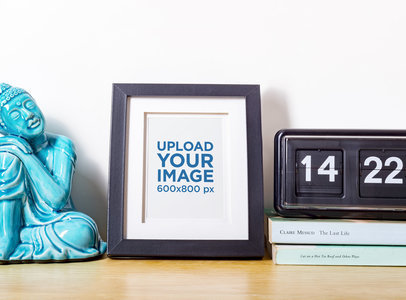 Mockup of a Photo Frame on a Table with a Buddha Statue