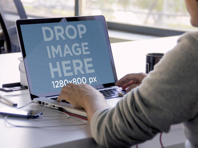 MacBook Mockup of a Man Working at an Office Table 