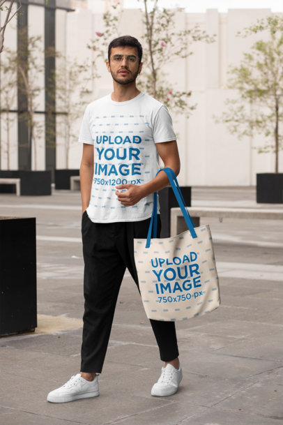 T-Shirt Mockup of a Man with a Customizable Strap Tote Bag Walking in the Street