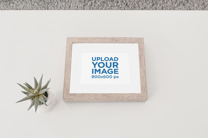 Wooden Picture Frame Mockup Placed Against a Flat Surface by an Indoor Plant