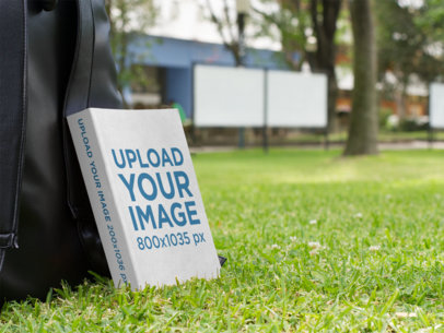 Ebook Mockup Leaning Against a Backpack in a Garden