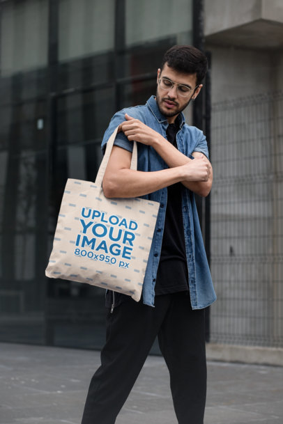 Tote Bag Mockup Featuring a Stylish Man Walking by a Modern Building 