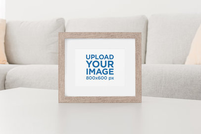 Mockup Featuring a Wooden Picture Frame Standing on a Living Room Table 